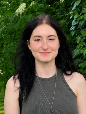 Portraitfoto von Marrey vor einer grünen Hecke